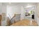 Upstairs hallway with a wood floor and wrought iron banister leading to bedroom with four-poster bed at 433 Sinaloa St, Waxhaw, NC 28173