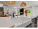 Open kitchen island with stainless faucet and sink, hardwood floors, and adjacent living room area at 433 Sinaloa St, Waxhaw, NC 28173