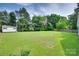 Expansive backyard with lush green lawn, mature trees, and storage shed, perfect for outdoor activities at 4712 Avalon Forest Ln, Charlotte, NC 28269
