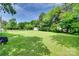 Expansive backyard with lush lawn, mature trees, storage shed, and wooden fence under a clear sky at 4712 Avalon Forest Ln, Charlotte, NC 28269