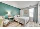 Cozy bedroom featuring light wood flooring, a comfortable bed, and a stylish teal accent wall at 4712 Avalon Forest Ln, Charlotte, NC 28269