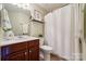 Well-lit bathroom with a cherry vanity, framed mirror, shower with curtain and tiled floors at 5046 Cressingham Dr, Fort Mill, SC 29707
