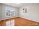 Cozy bedroom featuring hardwood floors, bright window, neutral paint, and a modern light fixture at 5046 Cressingham Dr, Fort Mill, SC 29707