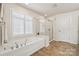 Luxurious main bathroom with a soaking tub, glass shower, and a window with shutter blinds at 5046 Cressingham Dr, Fort Mill, SC 29707