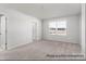 This is a light bedroom featuring plush neutral carpeting, a bright window, and access to a door at 5142 Tommy Ln # 1202, Stanley, NC 28164