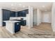 Open-concept kitchen boasts blue cabinets, a central island, stainless steel appliances, and sleek hardwood floors at 5142 Tommy Ln # 1202, Stanley, NC 28164