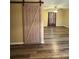 Open-concept living room featuring a rustic barn door and updated floors at 5420 Harkey Rd, Waxhaw, NC 28173