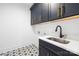 New laundry room with navy cabinets, gold hardware, stainless sink and striking patterned tile flooring at 550 W Cama St, Charlotte, NC 28217