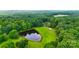 Vibrant aerial view showcasing the property with a pond surrounded by dense, lush forest at 6350 Mount Pleasant S Rd, Concord, NC 28025