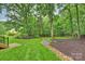 Backyard with beautiful landscaping, mature trees, a rock-lined drainage, and a lush green lawn at 6722 Elmstone Dr, Charlotte, NC 28277