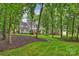 Back exterior with a deck overlooking the well manicured backyard with lush greenery and mature trees at 6722 Elmstone Dr, Charlotte, NC 28277