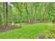 Landscaped backyard featuring mature trees, lush greenery, and a fenced perimeter for privacy at 6722 Elmstone Dr, Charlotte, NC 28277