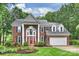 Charming brick two-story home with a red front door, manicured lawn, and lush landscaping at 6722 Elmstone Dr, Charlotte, NC 28277