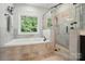 This bathroom features a soaking tub with a window view, a tiled shower with glass door, and neutral tiling at 7006 Nesbit Rd, Waxhaw, NC 28173