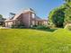 Expansive backyard with lush green lawn and mature trees, complemented by a black fence and pergola covered patio at 725 Old State Sw St, Concord, NC 28027