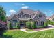 Stunning two-story home featuring a stone and brick facade, manicured lawn, and lush landscaping at 9807 Aristides Dr, Waxhaw, NC 28173