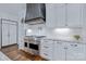 Close up of the kitchen range featuring a stainless steel vent hood, white cabinets, and herringbone backsplash at 9807 Aristides Dr, Waxhaw, NC 28173
