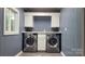Modern laundry room with front-loading machines, white cabinets, and a window for natural light at 109 Pepper Cir, Mooresville, NC 28117