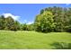 Expansive green backyard surrounded by trees and clear blue sky at 114 Wingard Rd, Concord, NC 28025