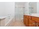 Well-lit bathroom features a bathtub, glass-enclosed shower, and double sink vanity at 11863 Ridgeway Park Dr, Charlotte, NC 28277