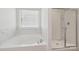 Bathroom showcasing a soaking tub with marble tile surround, and a glass-enclosed shower at 120 Mooring Dr, Statesville, NC 28677