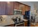 Kitchen with stainless steel appliances, dark wood cabinets, and granite countertops at 1225 Assembly St, Belmont, NC 28012