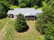 Aerial view of the property featuring a white house, metal roof, green lawn, and mature trees at 140 Dalu Ln, Harmony, NC 28634