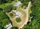 An aerial view shows a home and outbuildings set among lush greenery and a winding driveway at 140 Dalu Ln, Harmony, NC 28634