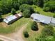 Aerial view of home, outbuilding, metal roofs, and surrounding trees on a well maintained lawn at 140 Dalu Ln, Harmony, NC 28634