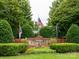 Landscaped community entrance with flags, a brick wall, and established shrubbery at 17119 Doe Valley Ct, Cornelius, NC 28031
