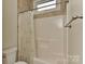 Bathroom with a shower and a window with light brown colored tiles and a floral curtain at 17210 Sulky Plough Rd # 1206, Charlotte, NC 28277