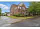 Charming brick townhome featuring manicured landscaping, lush green lawns, and mature trees at 3013 Coventry Commons Dr, Mint Hill, NC 28227
