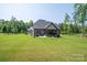 Wide view of the backyard featuring the home, patio, hot tub, and lush greenery at 4143 Willow Haven Dr, Denver, NC 28037