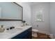 Bathroom with navy vanity, marble countertops, large mirror, window, and toilet in a well-lit space at 4143 Willow Haven Dr, Denver, NC 28037