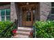 Elegant front entryway with brick steps, a wood door, and lush landscaping surrounding the entrance at 4143 Willow Haven Dr, Denver, NC 28037