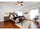 A sunlit bedroom features a ceiling fan, light walls, wood flooring and a decorative bench at the foot of the bed at 4683 Dunberry Sw Pl, Concord, NC 28027
