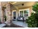 Inviting front porch with stone pillars, a black door, and a cozy seating area, perfect for relaxing outdoors at 4683 Dunberry Sw Pl, Concord, NC 28027