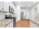 Modern kitchen with stainless steel appliances, granite countertops, white cabinetry, and wood-look flooring at 4848 Fonthill Ln, Charlotte, NC 28210