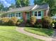 Charming brick home featuring a well-manicured lawn, vibrant green shutters, and a welcoming front entrance at 5806 Whitingham Dr, Charlotte, NC 28215