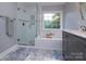 Light-filled bathroom with a glass-enclosed shower and soaking tub, offering a spa-like experience at home at 6914 Evanton Loch Rd, Charlotte, NC 28278