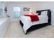 Cozy bedroom with neutral carpet, a queen-size bed with a bright red throw, and lots of natural light at 6914 Evanton Loch Rd, Charlotte, NC 28278