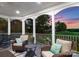 Enjoy the serene view from this covered patio with comfortable seating overlooking lush greenery and a colorful sunset at 7412 Sahalee Dr, Denver, NC 28037