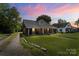 Charming red brick home with a welcoming front porch and lush green lawn at twilight at 85 Ruritan Park Rd, Stony Point, NC 28678
