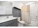 Bathroom featuring gray walls, a beige shower curtain, gray vanity with white sink, and beige tile floor at 9032 Cornflower Dr, Harrisburg, NC 28075