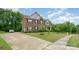 Beautiful two-story home with a long driveway, lush green lawn and mature trees at 9032 Cornflower Dr, Harrisburg, NC 28075