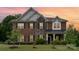 Elegant brick home featuring a stone facade, complemented by manicured landscaping and a welcoming front porch at 9032 Cornflower Dr, Harrisburg, NC 28075