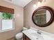 Bathroom featuring a wooden vanity, toilet, large round mirror, and window with natural light at 10710 Bristlecone Ct, Mint Hill, NC 28227