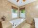 Bright bathroom featuring a soaking tub, tile surround, and natural light at 10710 Bristlecone Ct, Mint Hill, NC 28227