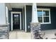 Inviting covered front porch with stone-accented columns and a stylish black front door entrance at 108 Red Juniper Way, Statesville, NC 28625