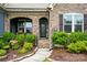 Close-up of a charming stone entrance with landscaped garden beds and a decorative front door at 10903 Skymont Dr, Huntersville, NC 28078